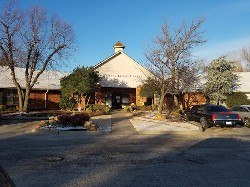 A serene view of a building surrounded by trees and a parking lot under clear blue skies.