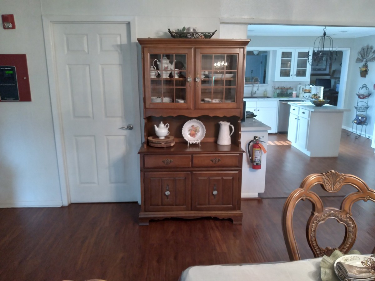A wooden china cabinet displayed in a dining room setting.