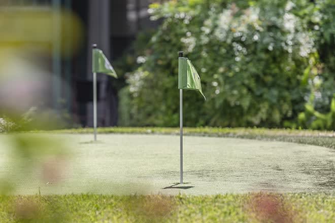 A serene outdoor putting green with two flags in the foreground.