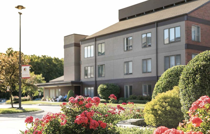 A hotel building with a garden featuring blooming flowers in the foreground.