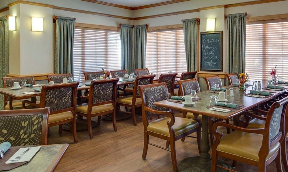 A neatly arranged dining area with multiple tables and chairs, featuring a menu board in the corner.