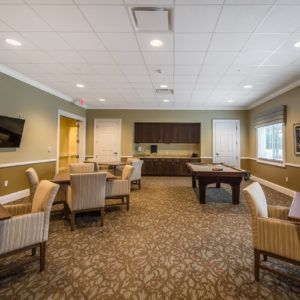 A cozy lounge area featuring several tables with chairs, a pool table, and a television.
