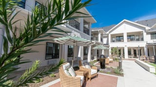 A modern patio with comfortable seating and umbrellas outside a contemporary house.