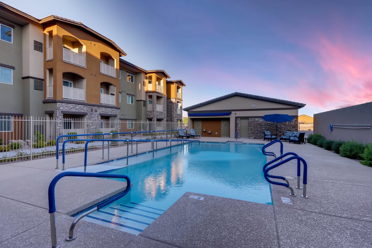 A serene outdoor pool area at an apartment complex during sunset.