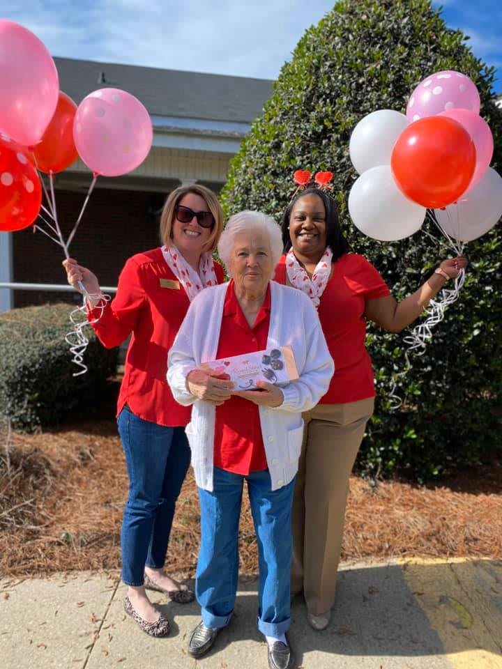 Group celebrating outdoors with balloons and festive attire.
