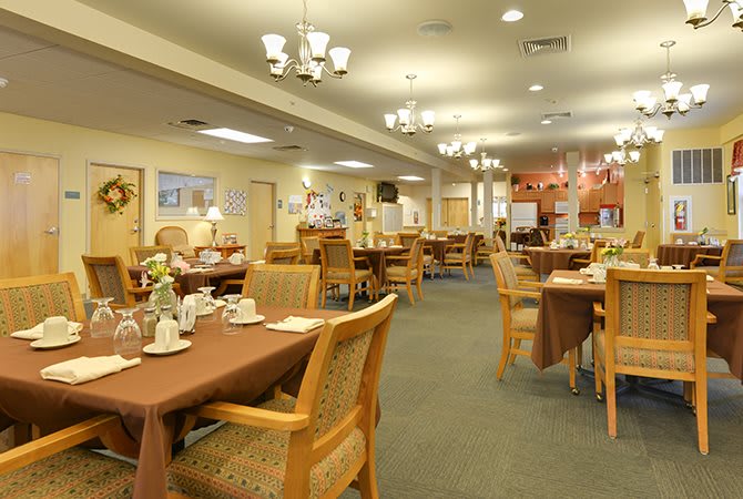 A cozy dining area with neatly arranged tables and chairs, warm lighting, and a welcoming ambiance.