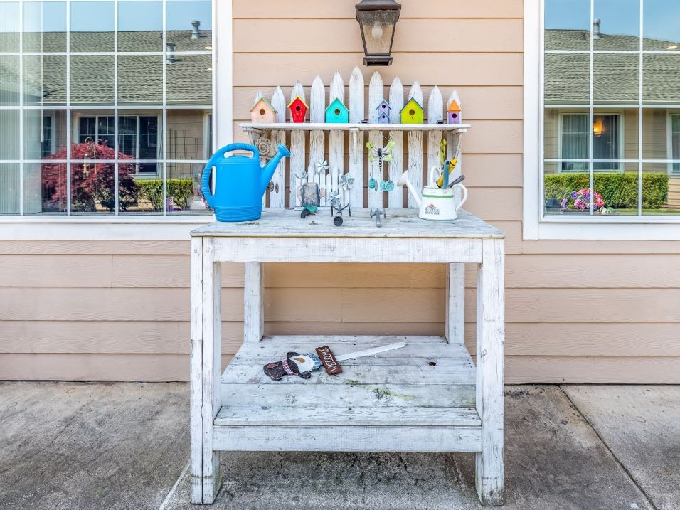 A rustic potting bench adorned with colorful birdhouses and garden tools.