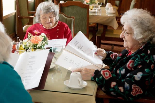 Two elderly women sitting at a restaurant table, looking at menus.