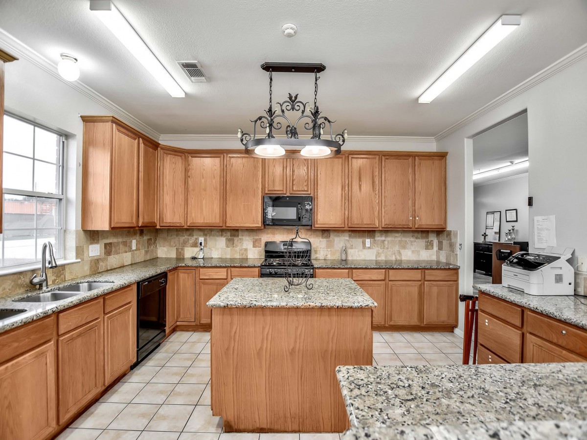 A spacious kitchen featuring wooden cabinets and a central island with granite countertops.