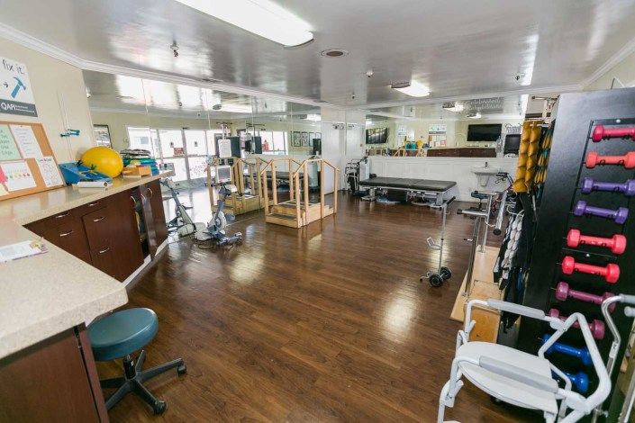 A rehabilitation center with various exercise equipment and therapy stations.