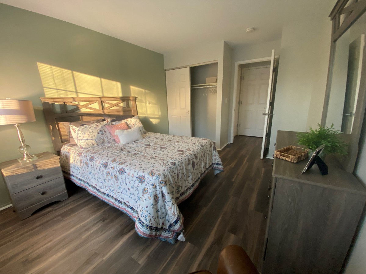 A cozy bedroom with a neatly made bed, illuminated by natural sunlight.