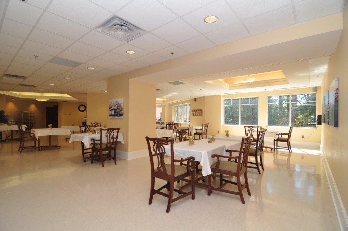 A spacious dining room area with neatly arranged tables and chairs under soft lighting.