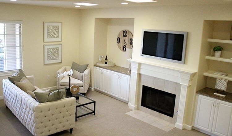 A cozy living room with a fireplace, wall-mounted TV, armchair, and coffee table.