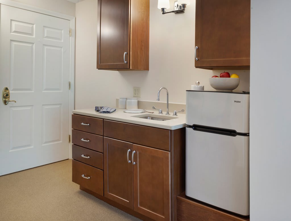 A compact kitchen area with wooden cabinets, a sink, and a small refrigerator.