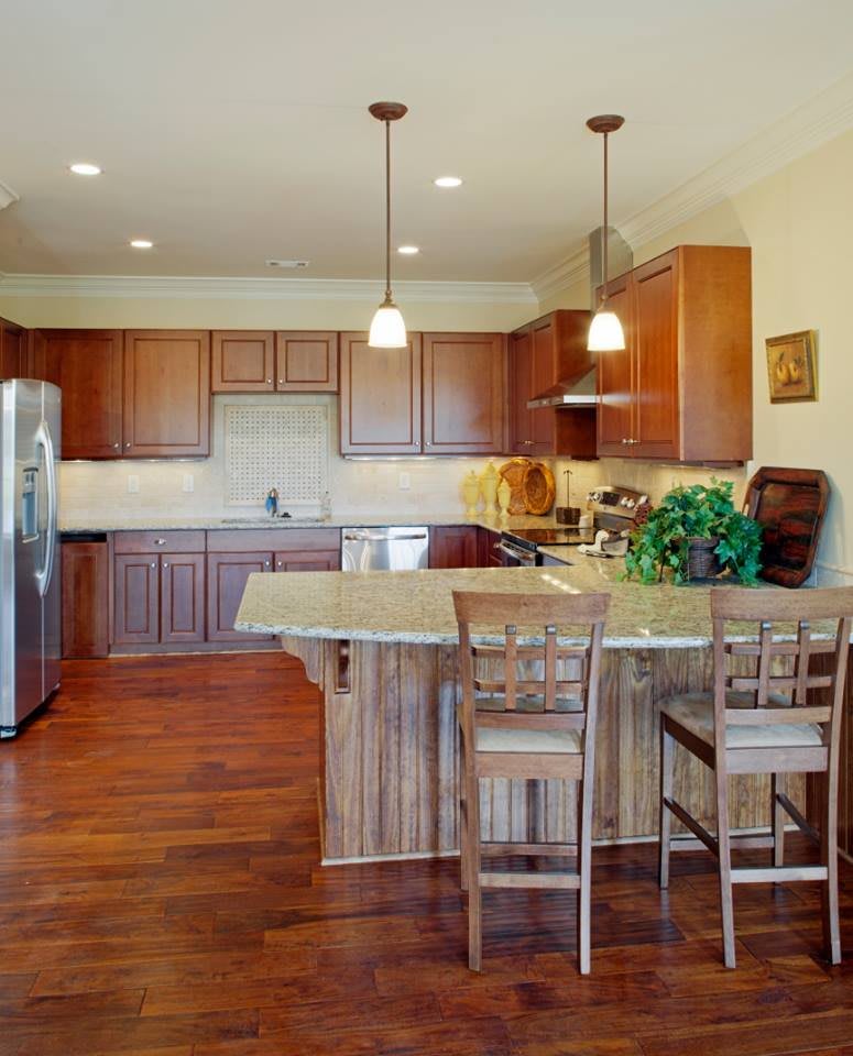 A spacious kitchen interior featuring wooden cabinets and a central island with pendant lighting.