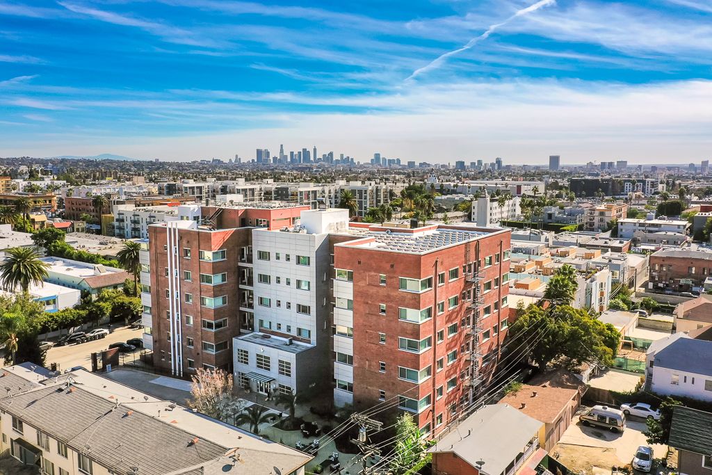 Aerial view of a residential apartment building with a city skyline in the background.