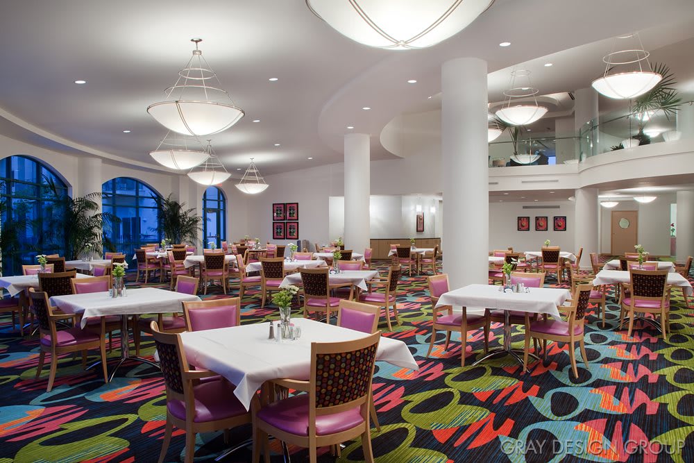 A spacious, modern restaurant interior with colorful carpet and well-arranged dining tables.