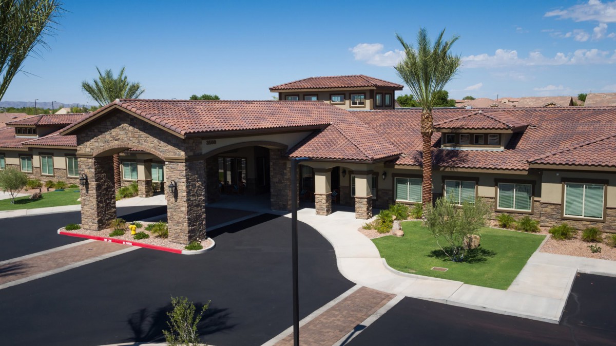 Aerial view of a luxury residential building with landscaped surroundings and palm trees.