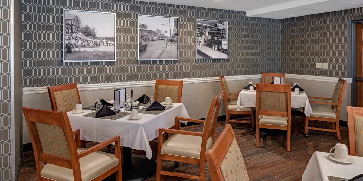 A neatly arranged dining area with tables and chairs, featuring artistic photographs on the wall.