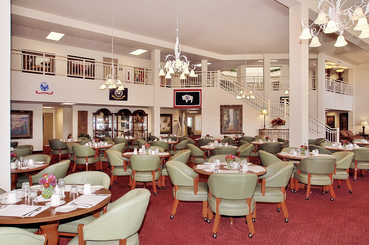 A spacious restaurant interior with neatly arranged tables and green chairs.