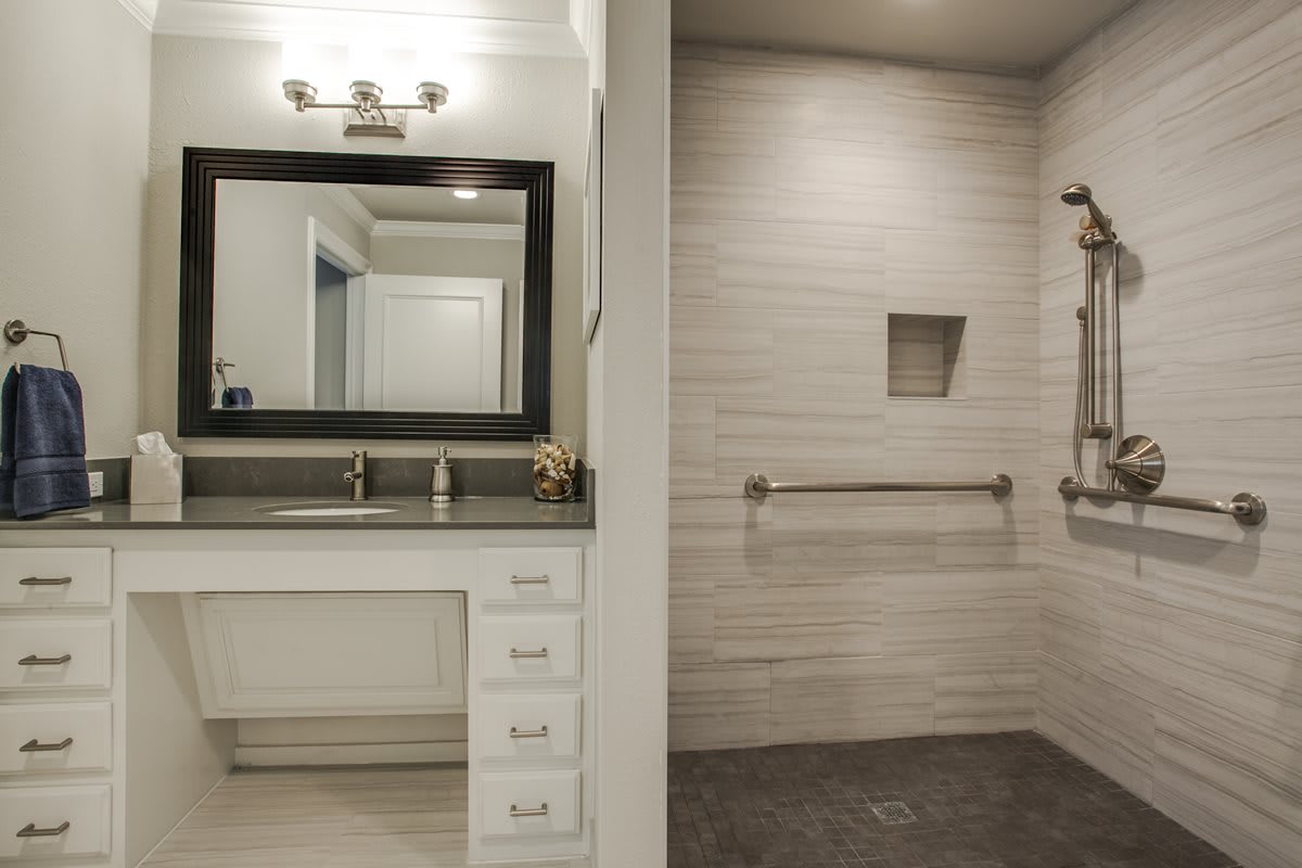A modern bathroom with a large vanity mirror and a walk-in shower featuring tiled walls.
