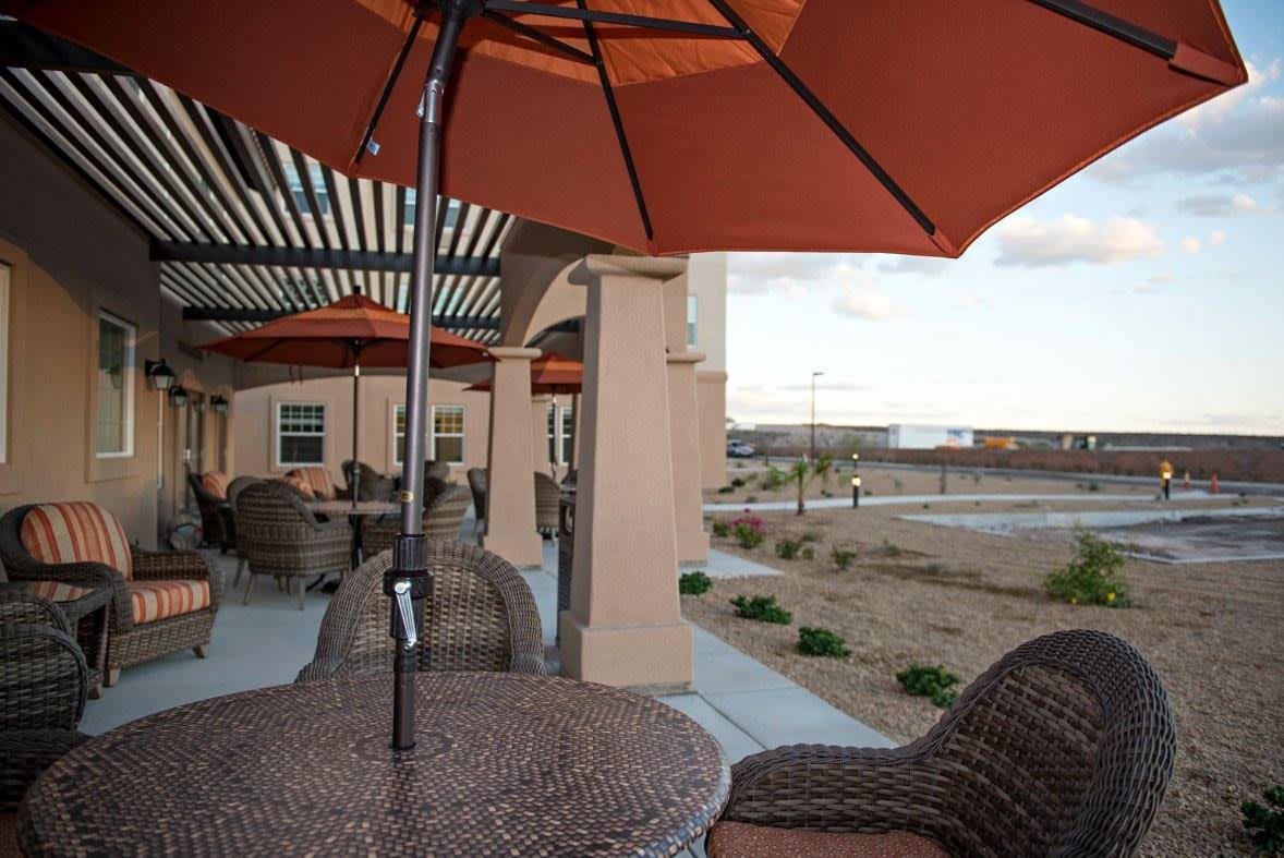 A cozy patio area with wicker chairs and orange umbrellas, overlooking an open landscape.