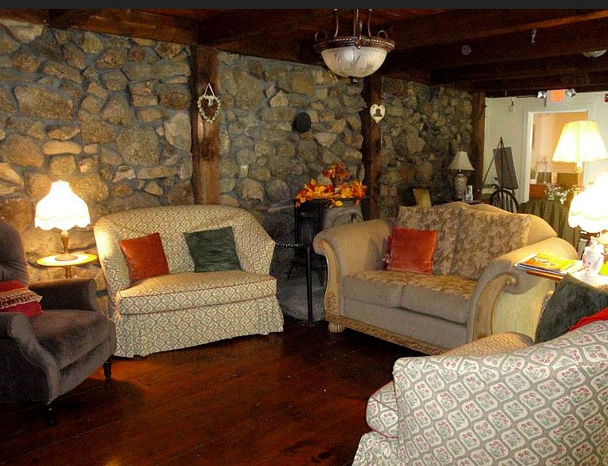 A cozy living room with stone walls, comfortable couches, and warm lighting.