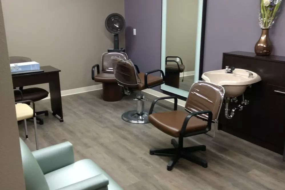 An interior view of a hair salon with chairs, a mirror, and a sink.
