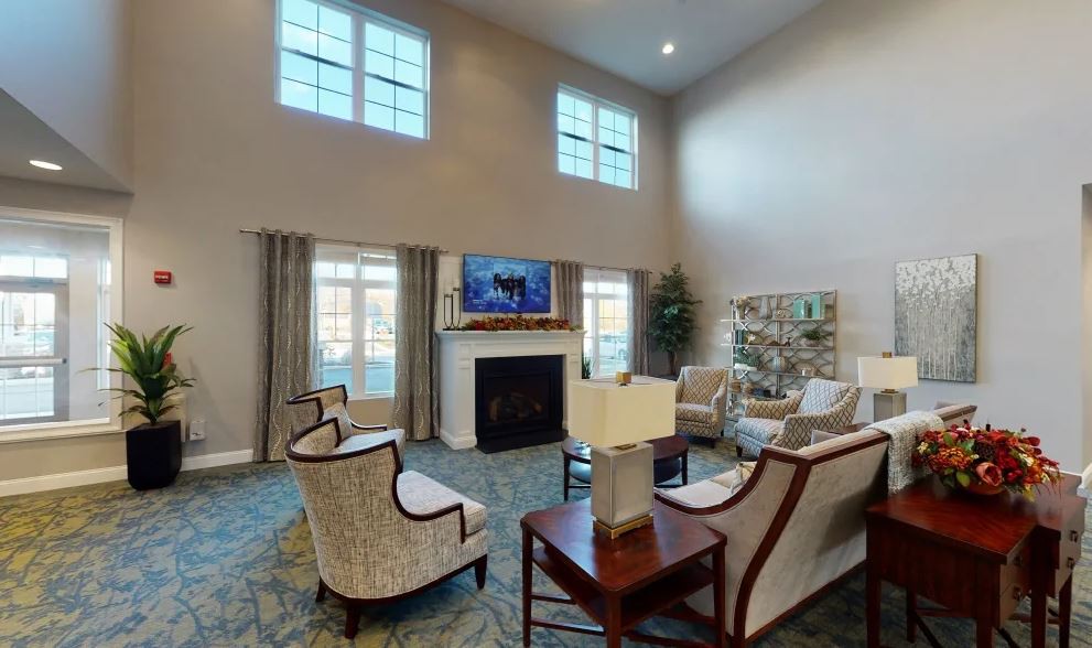 A spacious living room with high ceilings, featuring a large fireplace and arranged seating around a central table.