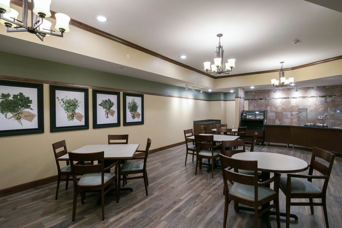 A cozy dining room with wooden tables and chairs, adorned with chandeliers and decorative artwork on the walls.