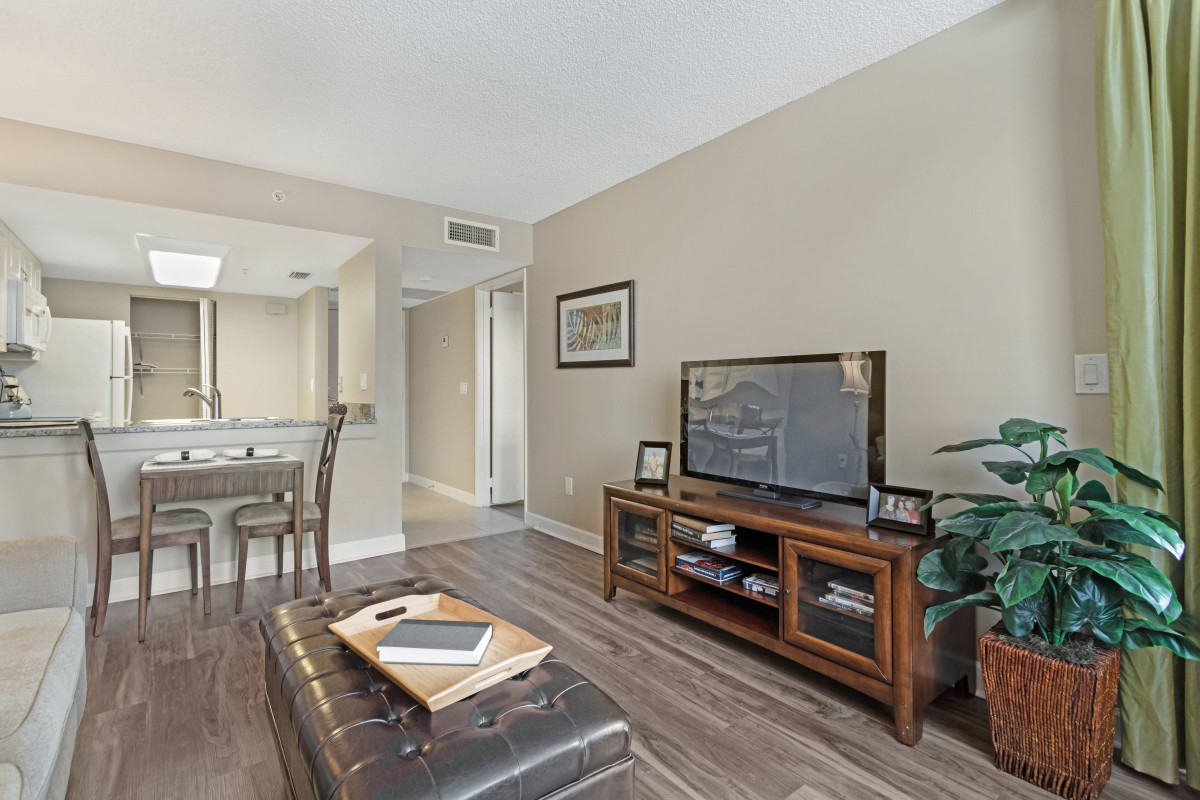 A cozy living room featuring modern furniture, a large TV stand, and elegant hardwood flooring.