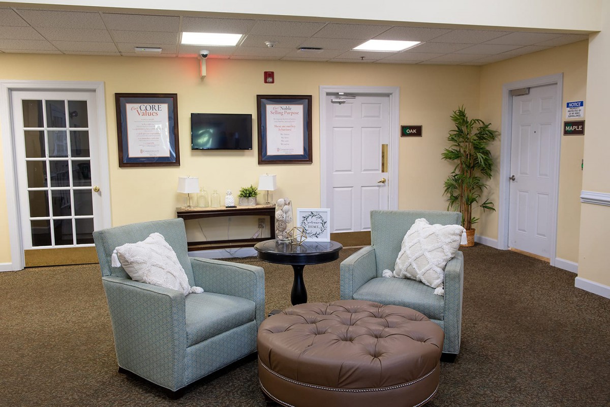 A cozy lobby seating area with chairs, an ottoman, and decorative elements.
