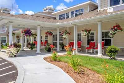 A charming building with a porch adorned with red chairs and hanging flower baskets.