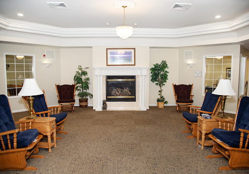 A cozy lounge area featuring comfortable seating and a fireplace, surrounded by indoor plants.