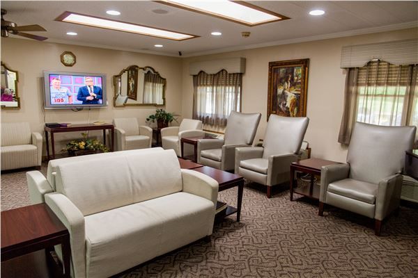 A well-furnished waiting room with comfortable seating and a television.