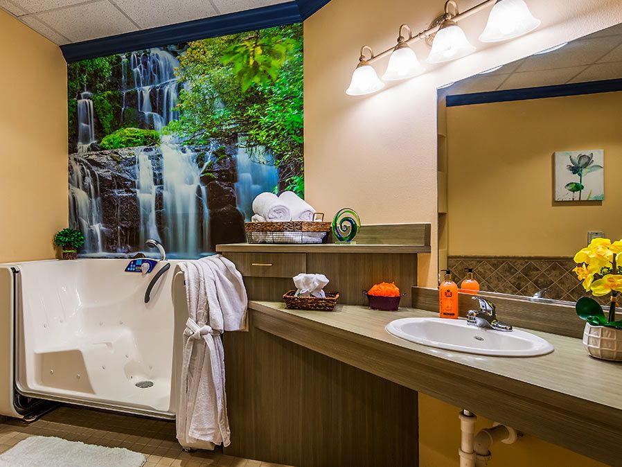 A luxurious bathroom with a soaking bathtub, large wall art of a waterfall, and elegant lighting.