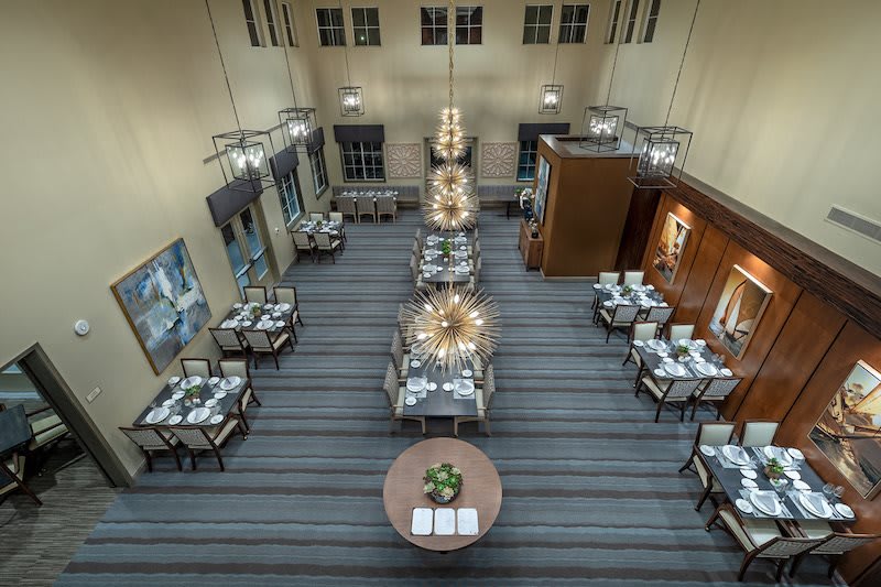 An elegant dining area with neatly arranged tables and exquisite chandeliers.