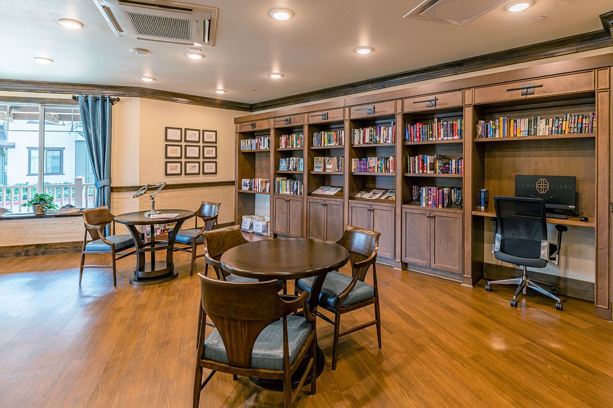 A cozy reading room with bookshelves, tables, and chairs.