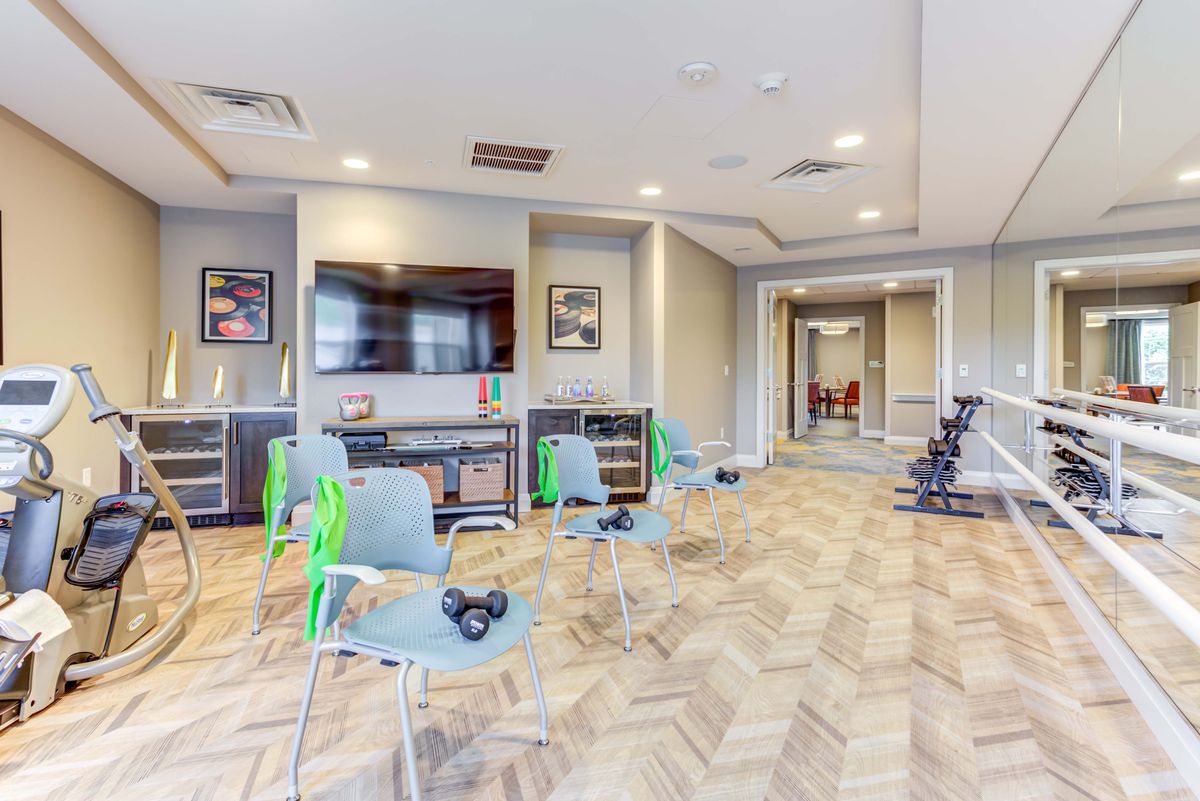 A modern fitness room with exercise equipment and seating.