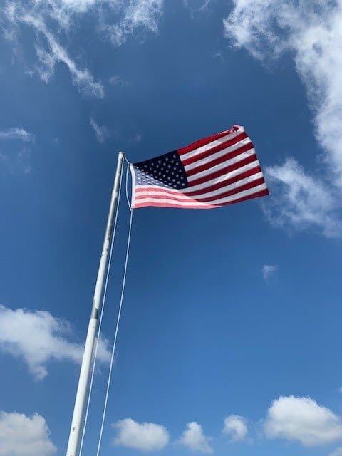 An American flag waves against a clear blue sky.