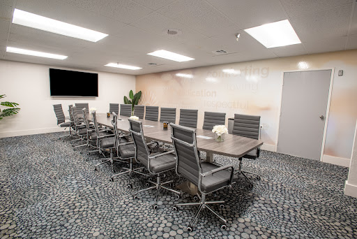 A modern conference room featuring a long table and ergonomic chairs, designed for professional meetings.