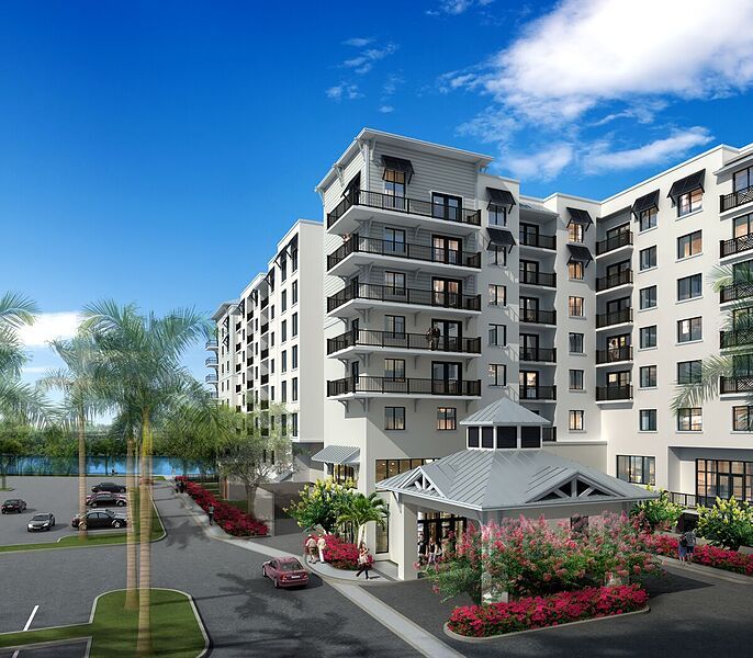A modern apartment building with balconies and landscaped surroundings under a clear blue sky.