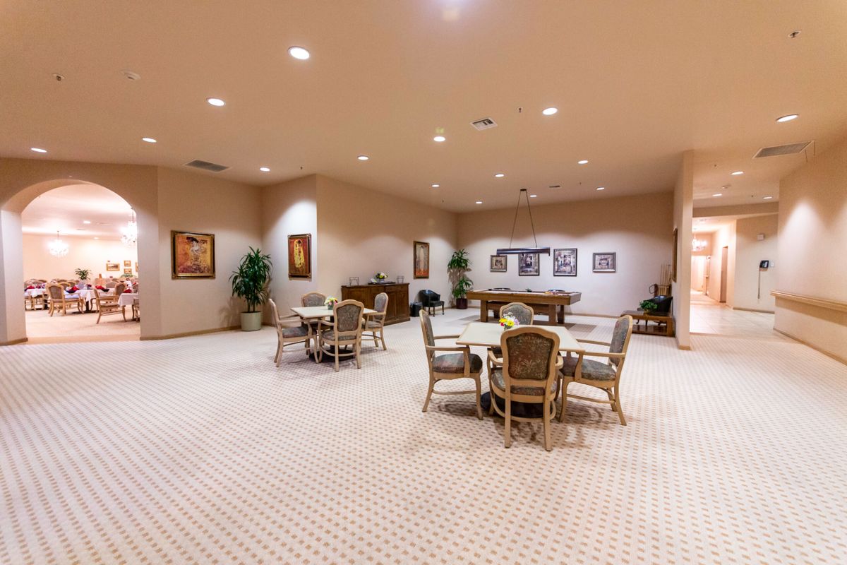 A spacious conference room with multiple round tables and chairs, decorated with plants and artwork.