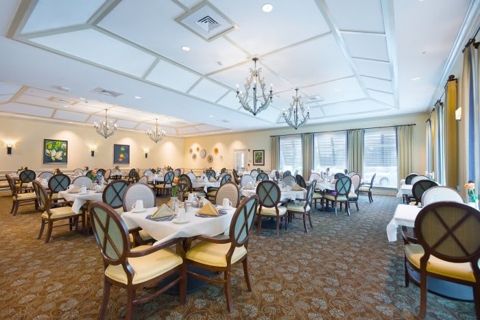 Elegant dining room with neatly arranged tables and chandeliers.