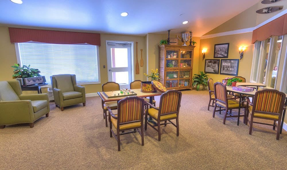 A cozy living room with a bookshelf, chairs, and a table.