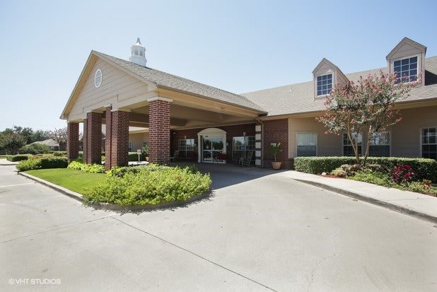 A building with a covered entrance and landscaped surroundings.