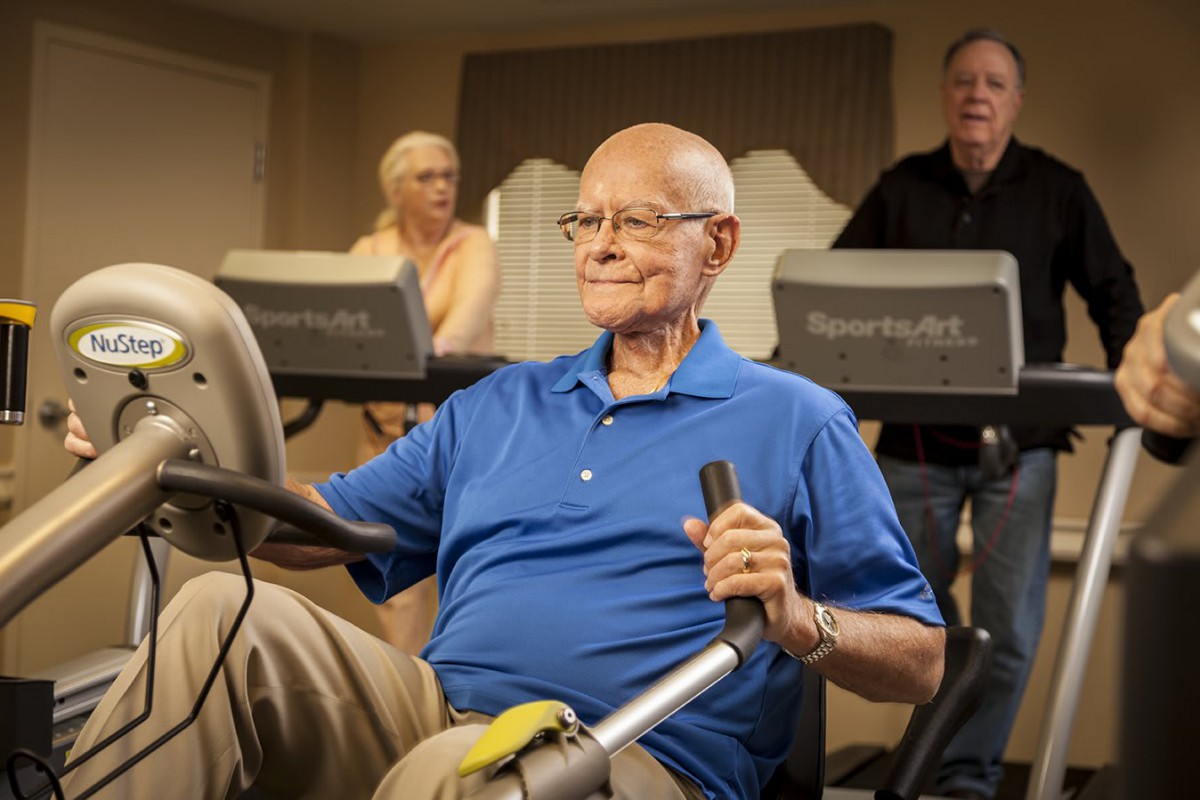 Elderly individuals exercising on gym equipment.