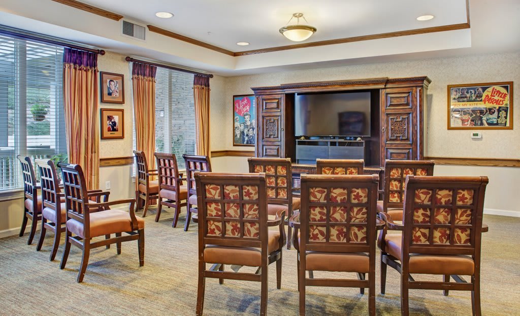 A well-appointed conference room with wooden chairs arranged facing a projector screen, complemented by framed artwork on the walls.