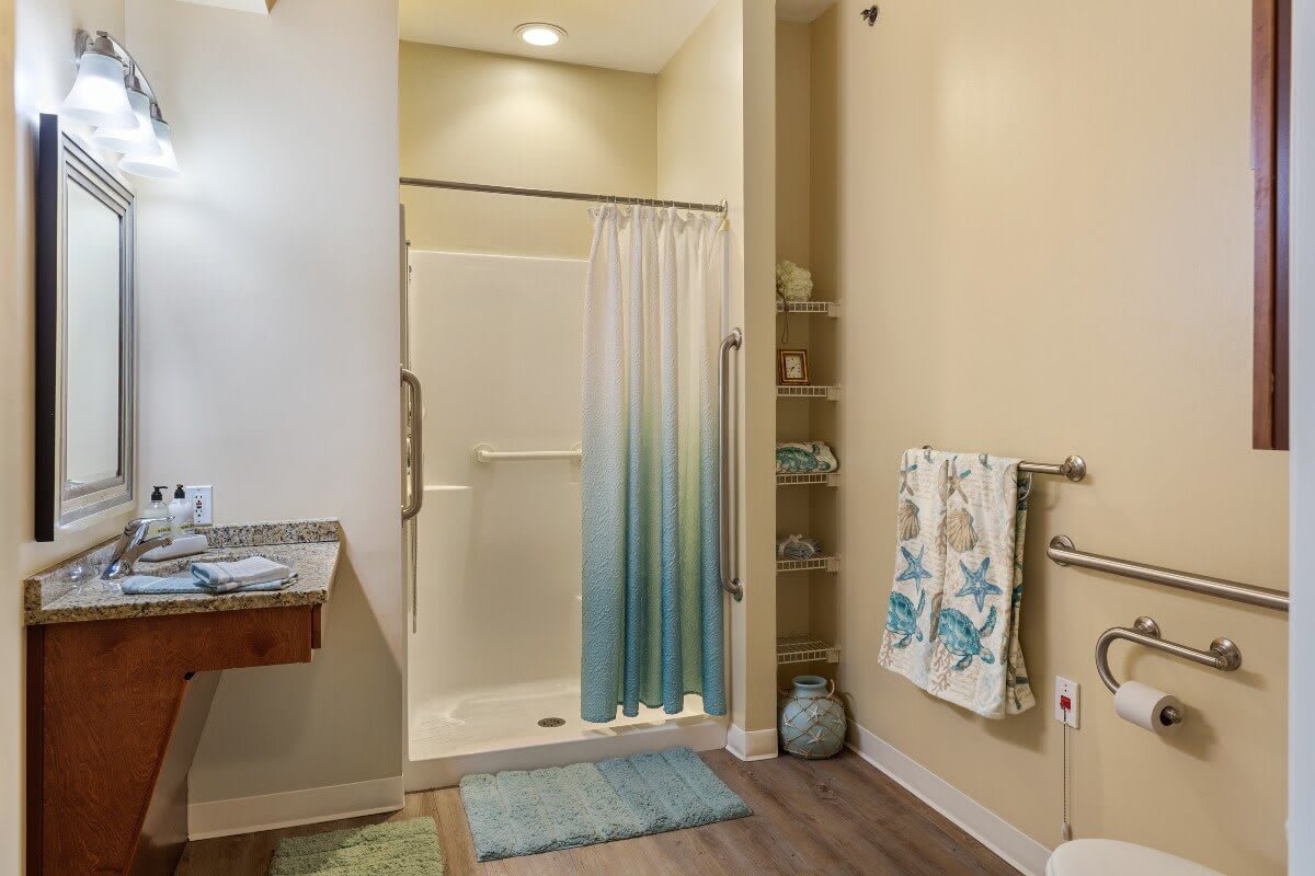 A well-organized bathroom featuring a shower with a gradient curtain, neatly arranged towels, and shelving for additional storage.