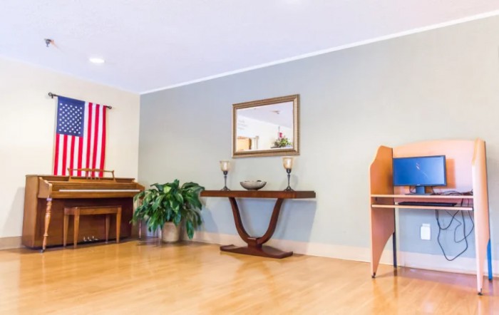 A cozy living room with a piano, console table, and a potted plant.